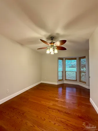 a view of empty room with wooden floor and fan