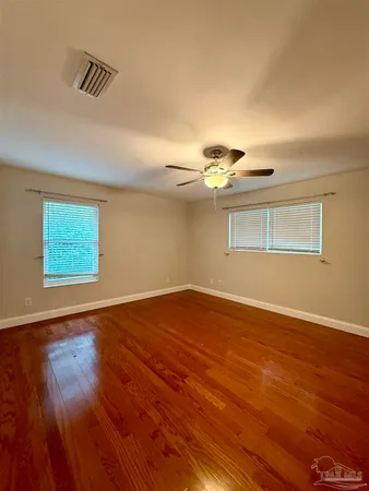 a view of empty room with wooden floor and fan