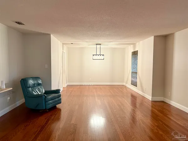 a view of a livingroom with wooden floor and furniture