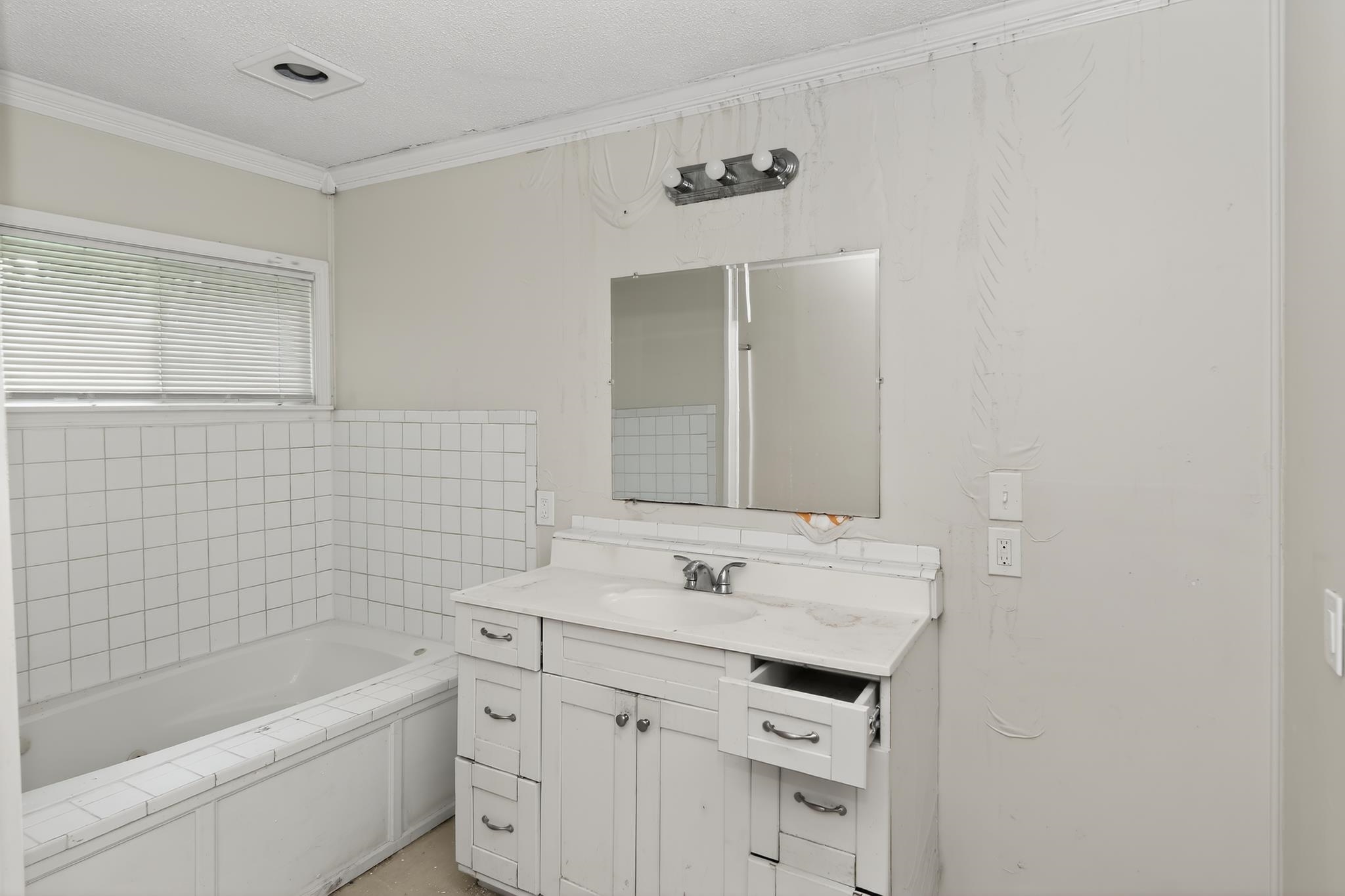 1403 Old Hickory Road Memphis, TN 38116 - Photo 22 of 31 Bathroom featuring a white vanity with integrated sink, a built-in bathtub with white tile surround, and a window with blinds