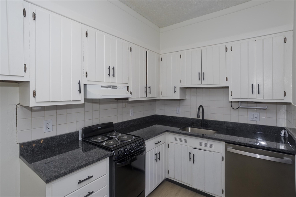 140 Chestnut Street, Unit 404 Springfield, MA 01103 - Photo 8 of 15 a kitchen with granite countertop white cabinets and black appliances