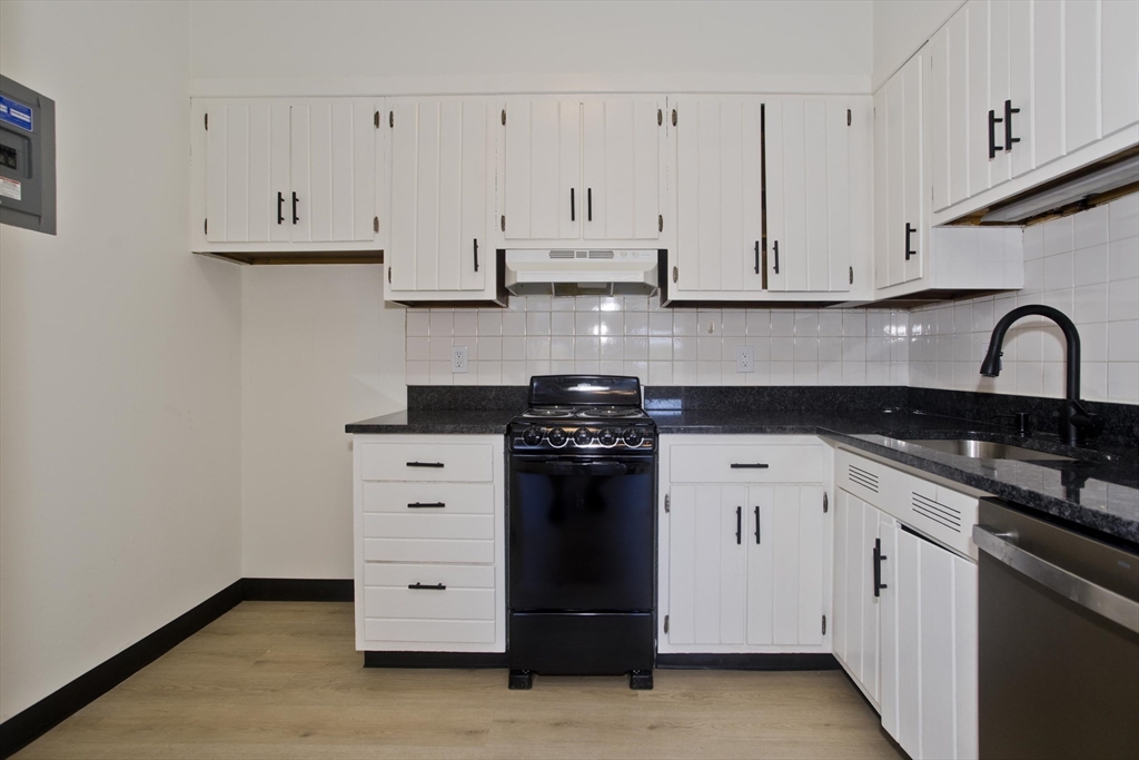 140 Chestnut Street, Unit 404 Springfield, MA 01103 - Photo 9 of 15 a kitchen with white cabinets and black appliances