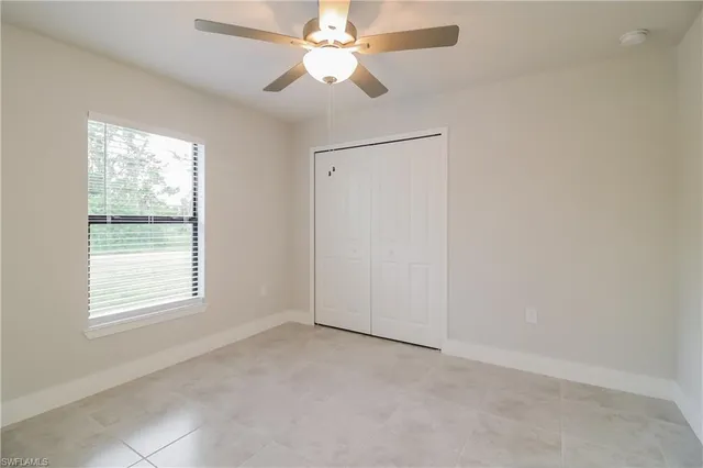 an empty room with a window and a fan