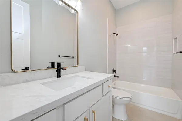 a bathroom with a granite countertop sink toilet a mirror and bathtub
