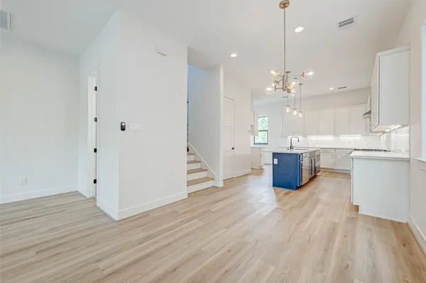 an empty room with wooden floor and kitchen view
