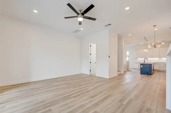 an empty room with wooden floor and a ceiling fan