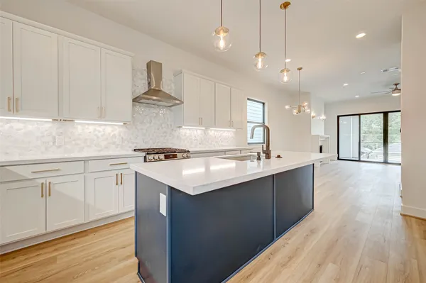 a kitchen with kitchen island granite countertop a sink cabinets and wooden floor