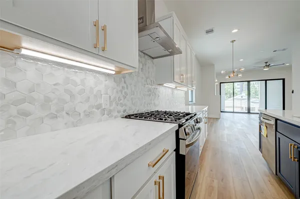 a kitchen with stainless steel appliances granite countertop a stove and a wooden floors