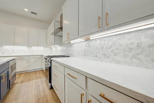 a kitchen with a sink dishwasher and white cabinets with wooden floor