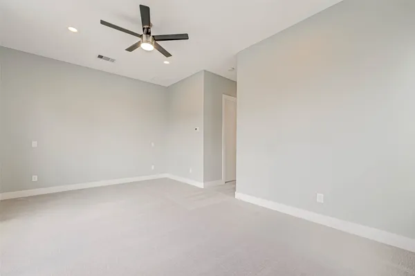an empty room with a ceiling fan and carpet