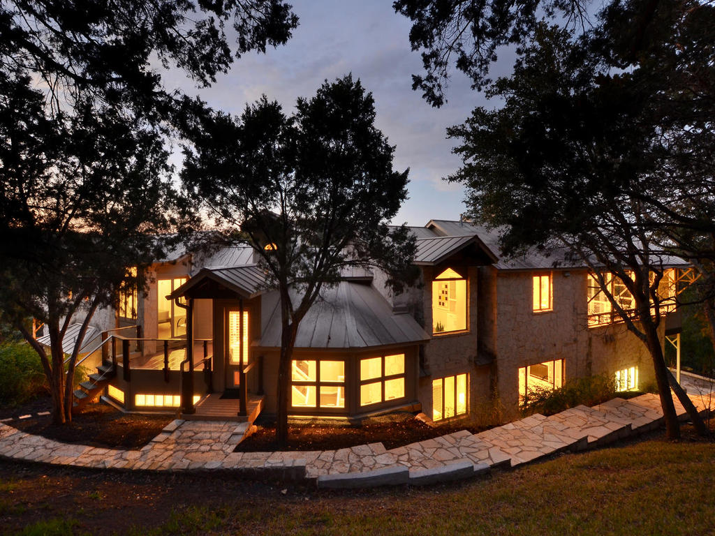 a front view of a house with a yard and large trees