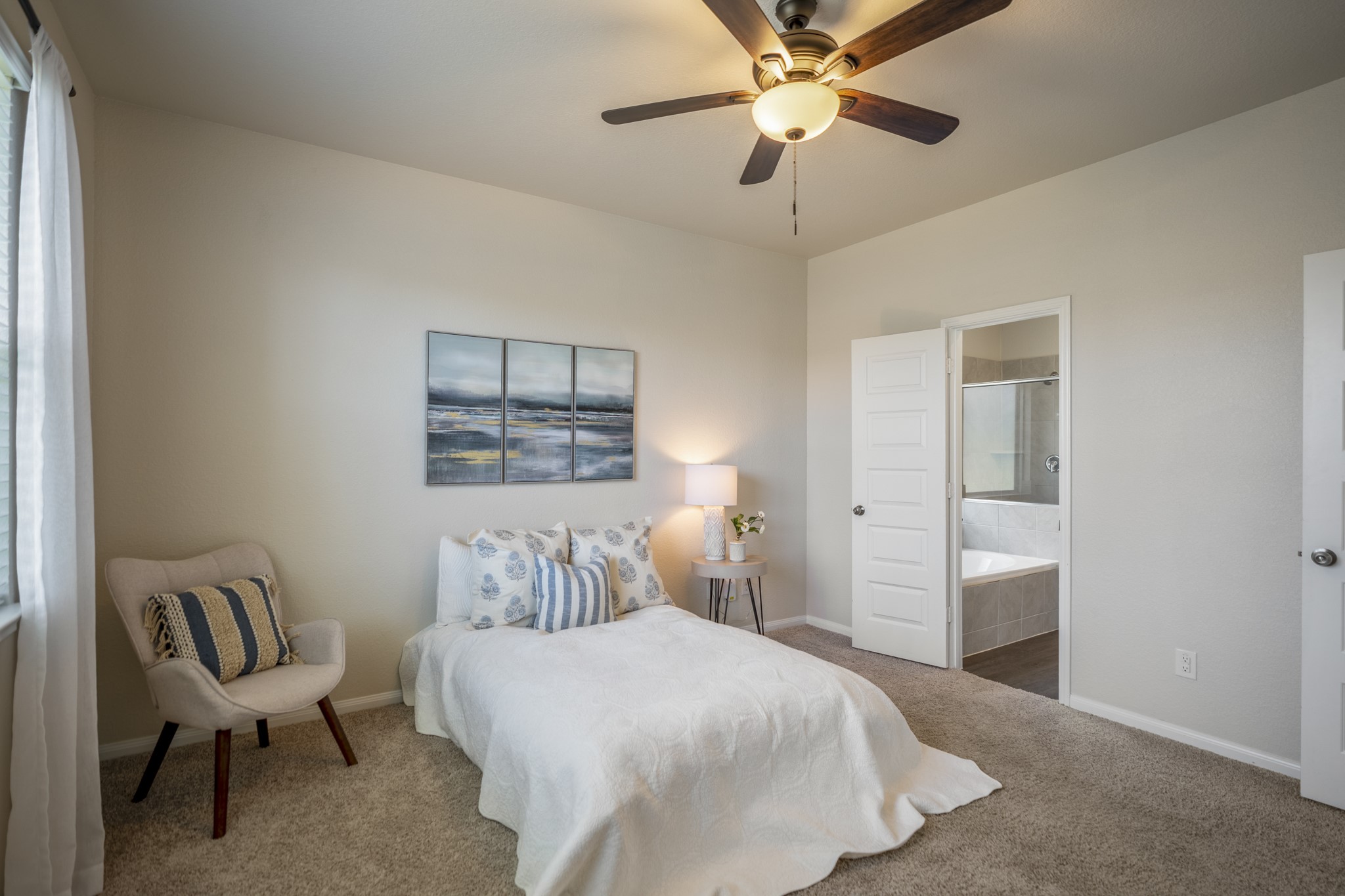 2355 Mount Locke Path Conroe, TX 77301 - Photo 18 of 47 A second angle of the primary suite shows the room’s natural light from the side window and the easy path into the bath through the open doorway ahead.