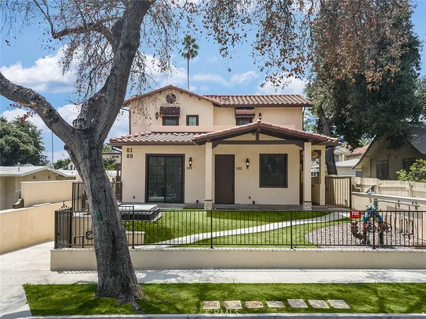 a front view of a house with a garden and trees