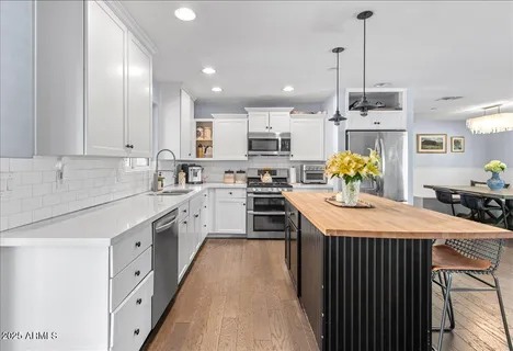 a kitchen with kitchen island granite countertop a sink a counter top space stainless steel appliances and cabinets