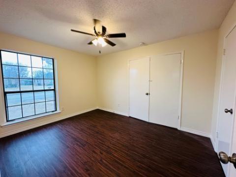 205 Apollo Road Garland, TX 75040 - Photo 4 of 6 an empty room with wooden floor fan and windows