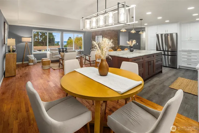 a kitchen with stainless steel appliances kitchen island granite countertop a table chairs and a living room