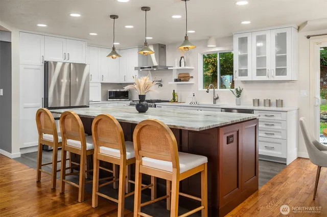 a kitchen with stainless steel appliances granite countertop a table chairs sink refrigerator and microwave