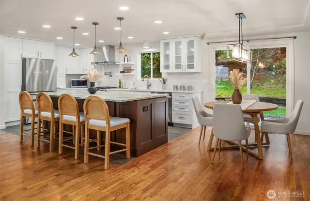 a dining room with stainless steel appliances granite countertop a dining table chairs refrigerator and sink