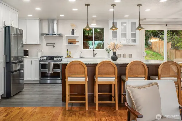 a kitchen with stainless steel appliances granite countertop a table chairs sink refrigerator and microwave