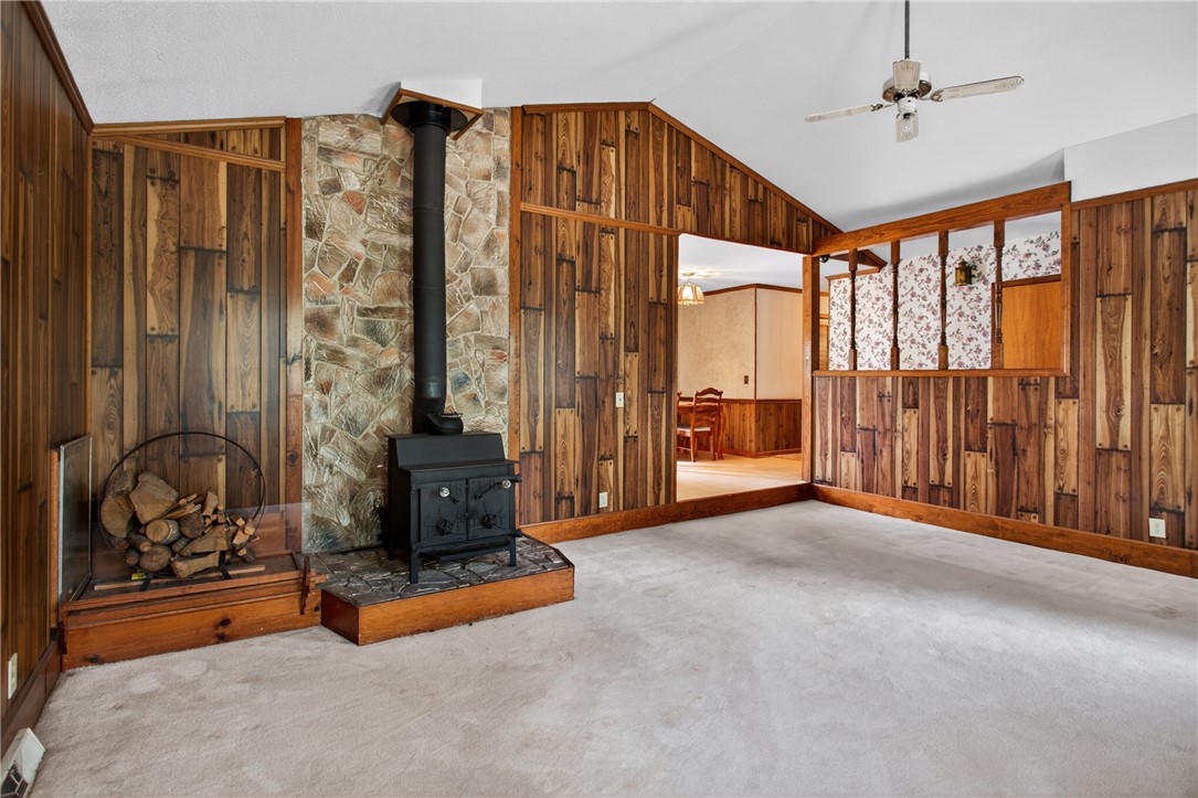 112 Holliday Lane Pendleton, SC 29670 - Photo 7 of 42 A cozy living space features a rustic wood-burning stove set against a stone and wood-paneled accent wall.
