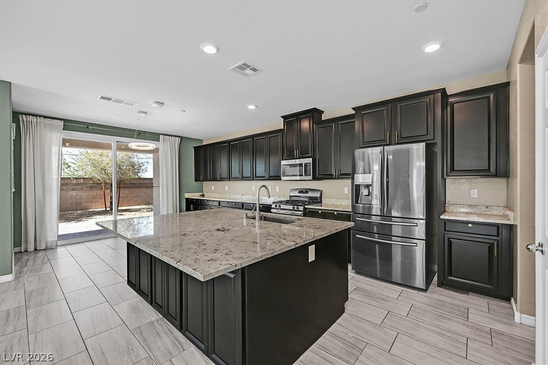 1106 Langston Ranch Avenue Henderson, NV 89002 - Photo 7 of 36 Prepare meals in a kitchen featuring an expansive granite-topped island and abundant cabinetry.