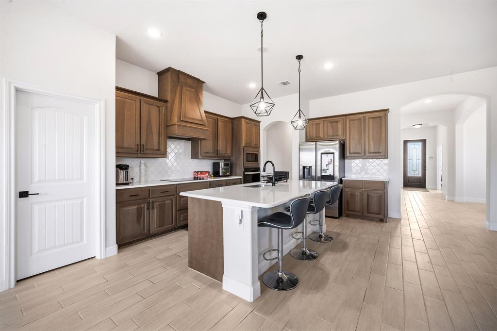 3841 Eagles Bluff Road Midlothian, TX 76065 - Photo 13 of 36 a kitchen with kitchen island a stove a sink a center island a refrigerator and a wooden floor