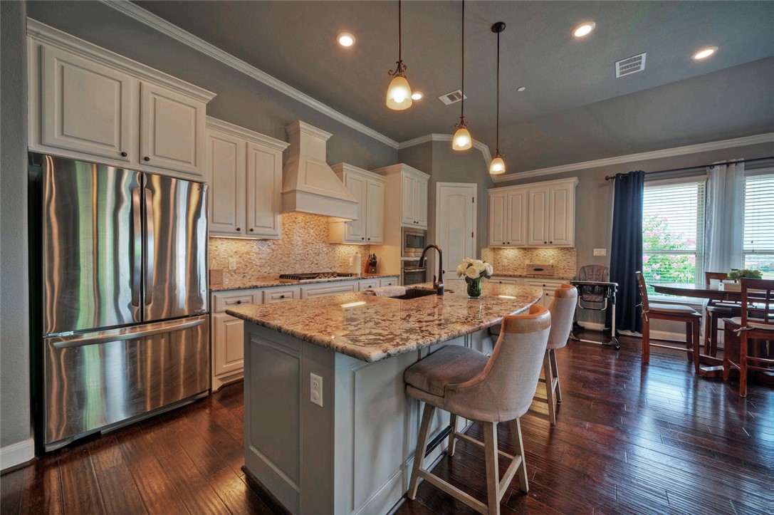 101 Maxwell Way Austin, TX 78738 - Photo 14 of 40 a kitchen with stainless steel appliances granite countertop a refrigerator a sink dishwasher a dining table and chairs with wooden floor
