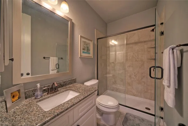 a bathroom with a granite countertop sink toilet mirror and shower