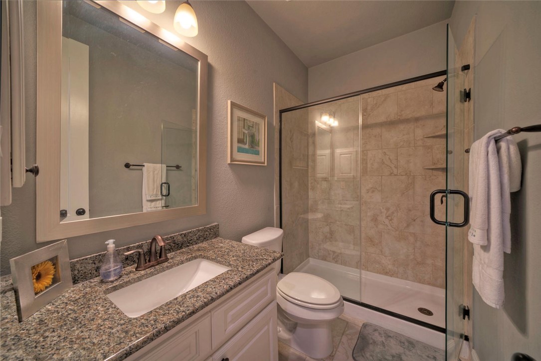 101 Maxwell Way Austin, TX 78738 - Photo 24 of 40 a bathroom with a granite countertop sink toilet mirror and shower