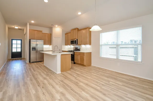 a large kitchen with stainless steel appliances granite countertop a stove and a wooden floors
