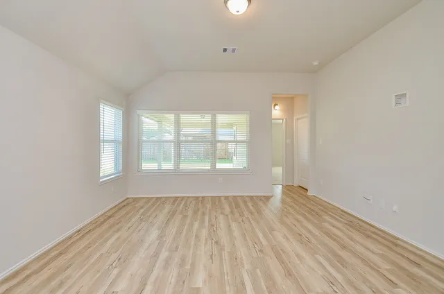 an empty room with wooden floor and windows