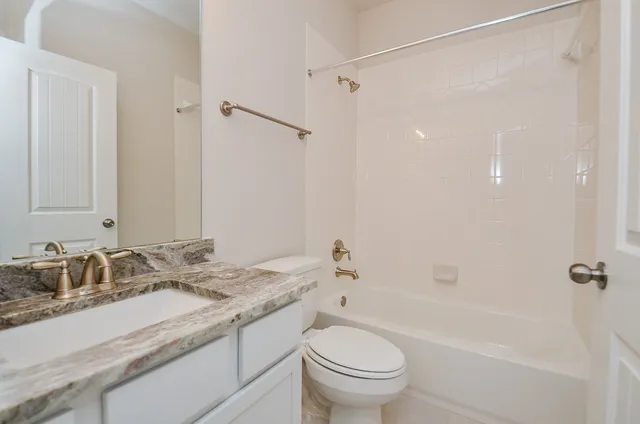 a bathroom with a granite countertop sink a toilet and shower
