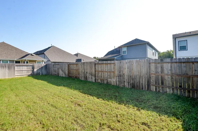 a view of a house with a yard and wooden fence