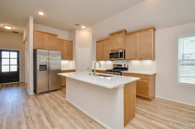 a kitchen with kitchen island a refrigerator sink and stove
