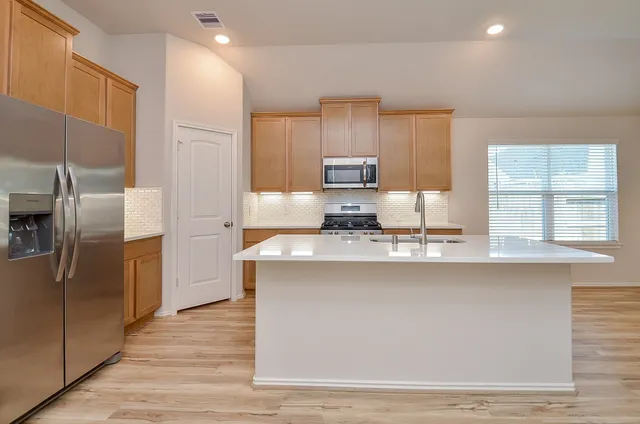 a kitchen with stainless steel appliances granite countertop a stove a sink and a refrigerator