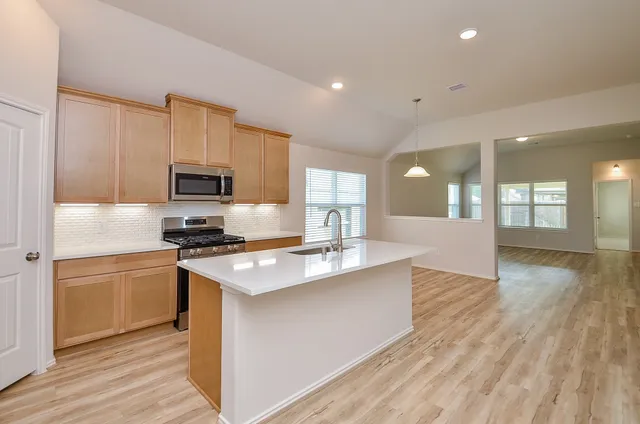 a kitchen with stainless steel appliances a stove top oven a sink dishwasher and a refrigerator