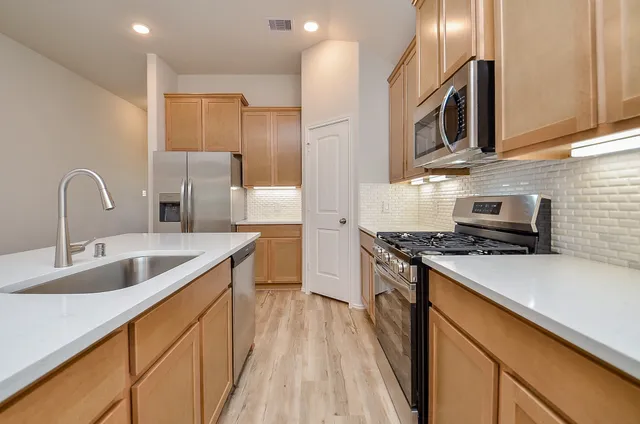 a kitchen with stainless steel appliances granite countertop a sink stove and refrigerator