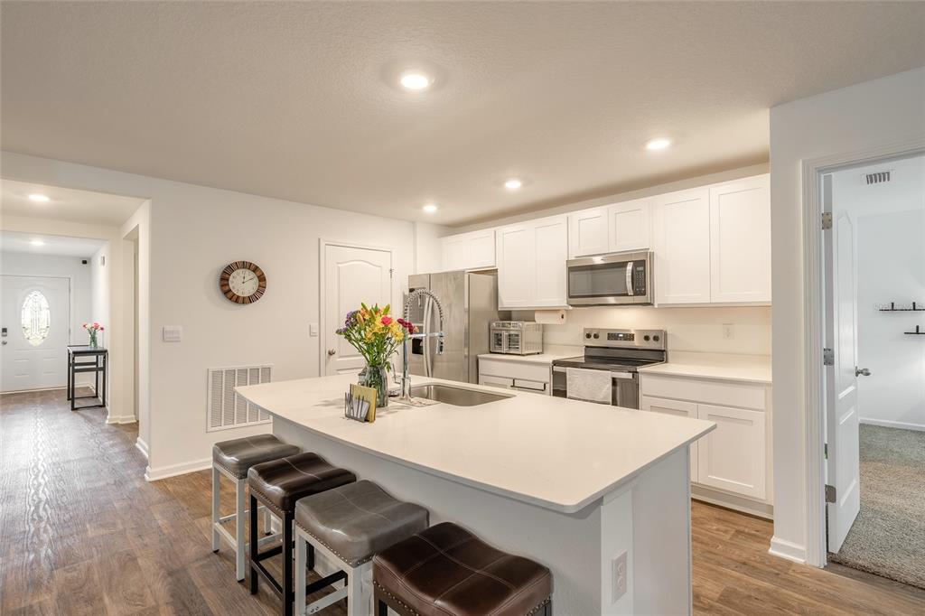 82 Hulett Wds Road Palm Coast, FL 32137 - Photo 6 of 48 a kitchen with stainless steel appliances granite countertop a stove a refrigerator a kitchen island a dining table and chairs with wooden floor