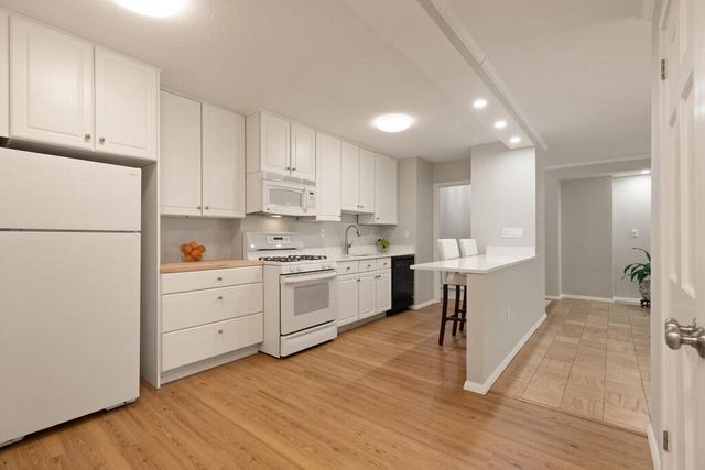 a kitchen with white cabinets and white appliances