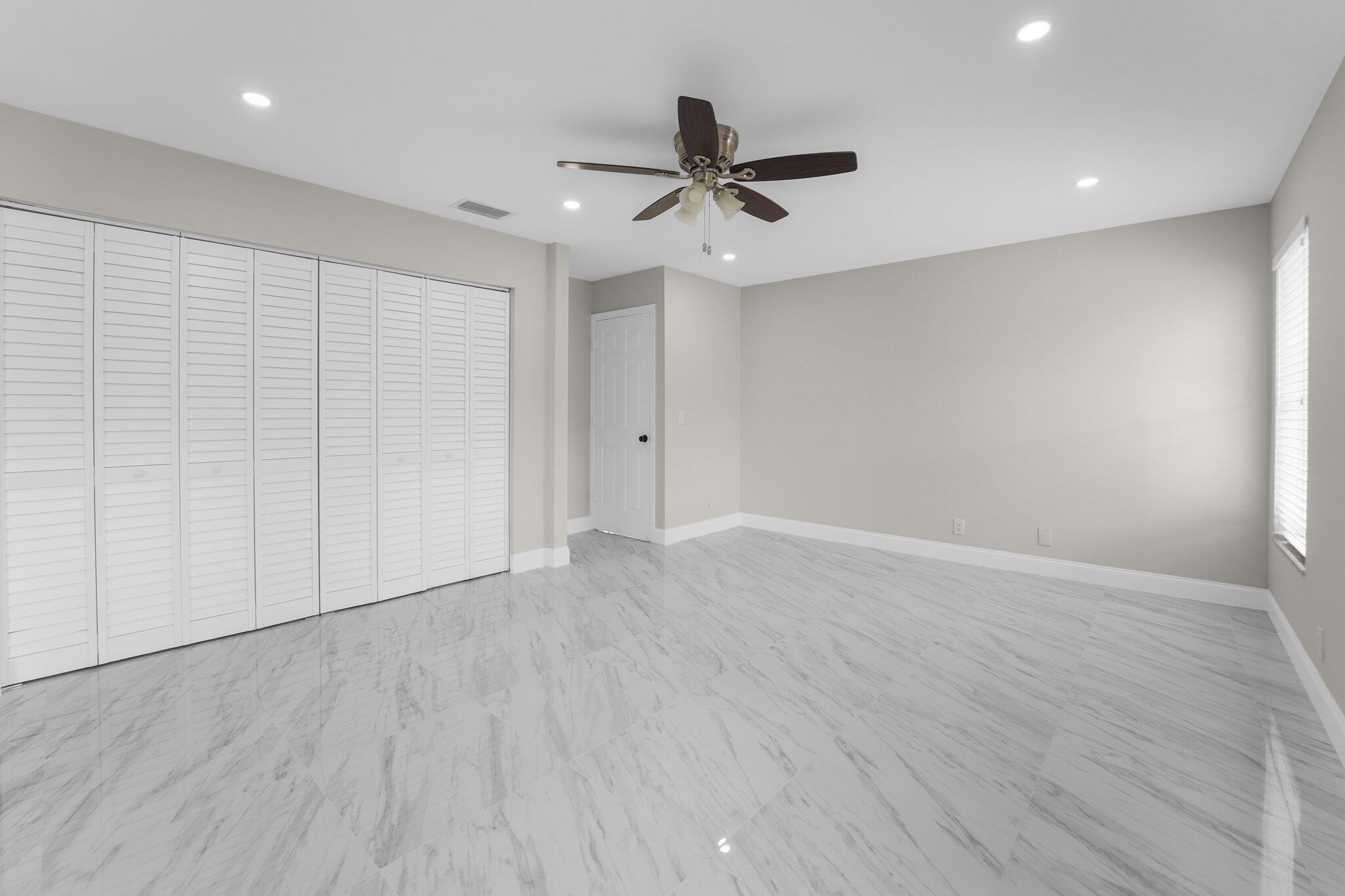 22207 Alyssum Way Boca Raton, FL 33433 - Photo 13 of 31 an empty room with wooden floor a ceiling fan and windows