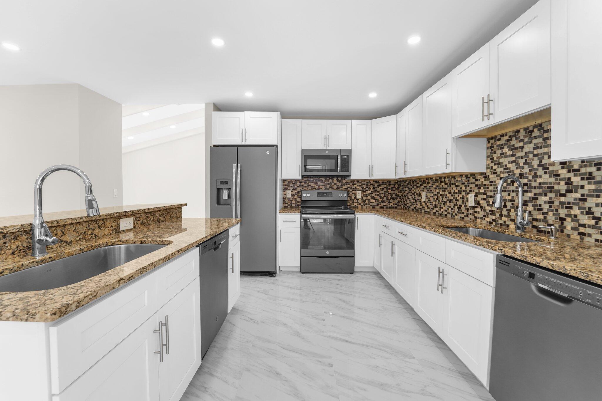 22207 Alyssum Way Boca Raton, FL 33433 - Photo 4 of 31 a large kitchen with stainless steel appliances kitchen island granite countertop a sink and cabinets