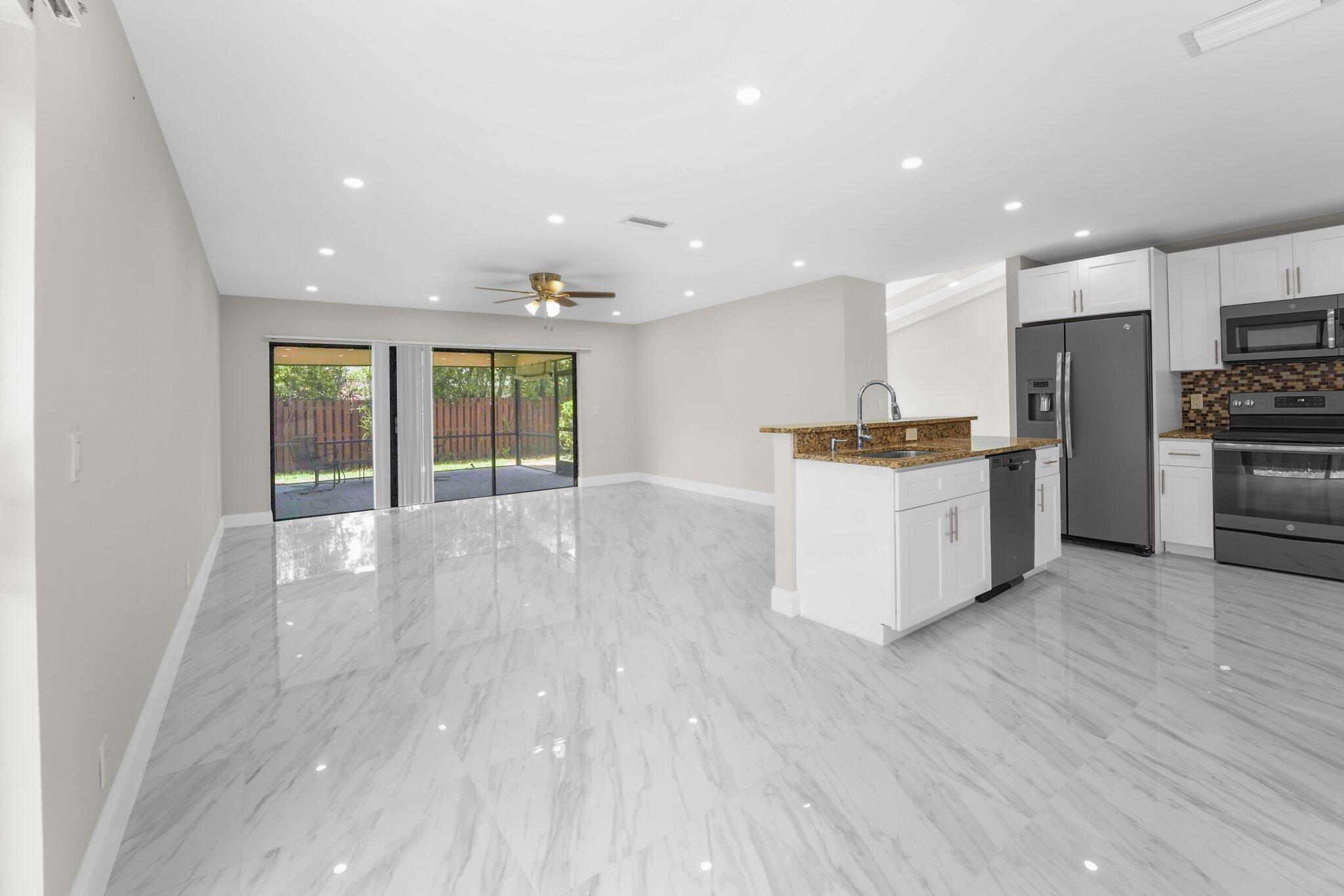 22207 Alyssum Way Boca Raton, FL 33433 - Photo 6 of 31 a kitchen with stainless steel appliances kitchen island wooden cabinets and granite counter tops