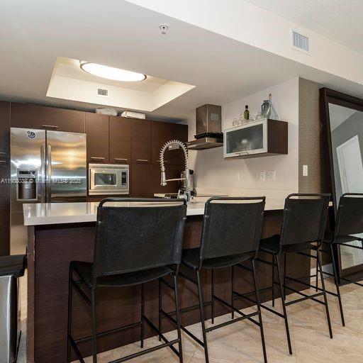 200 Sunny Isles Boulevard, Unit 2604 Sunny Isles Beach, FL 33160 - Photo 12 of 36 a kitchen with a table chairs microwave and cabinets