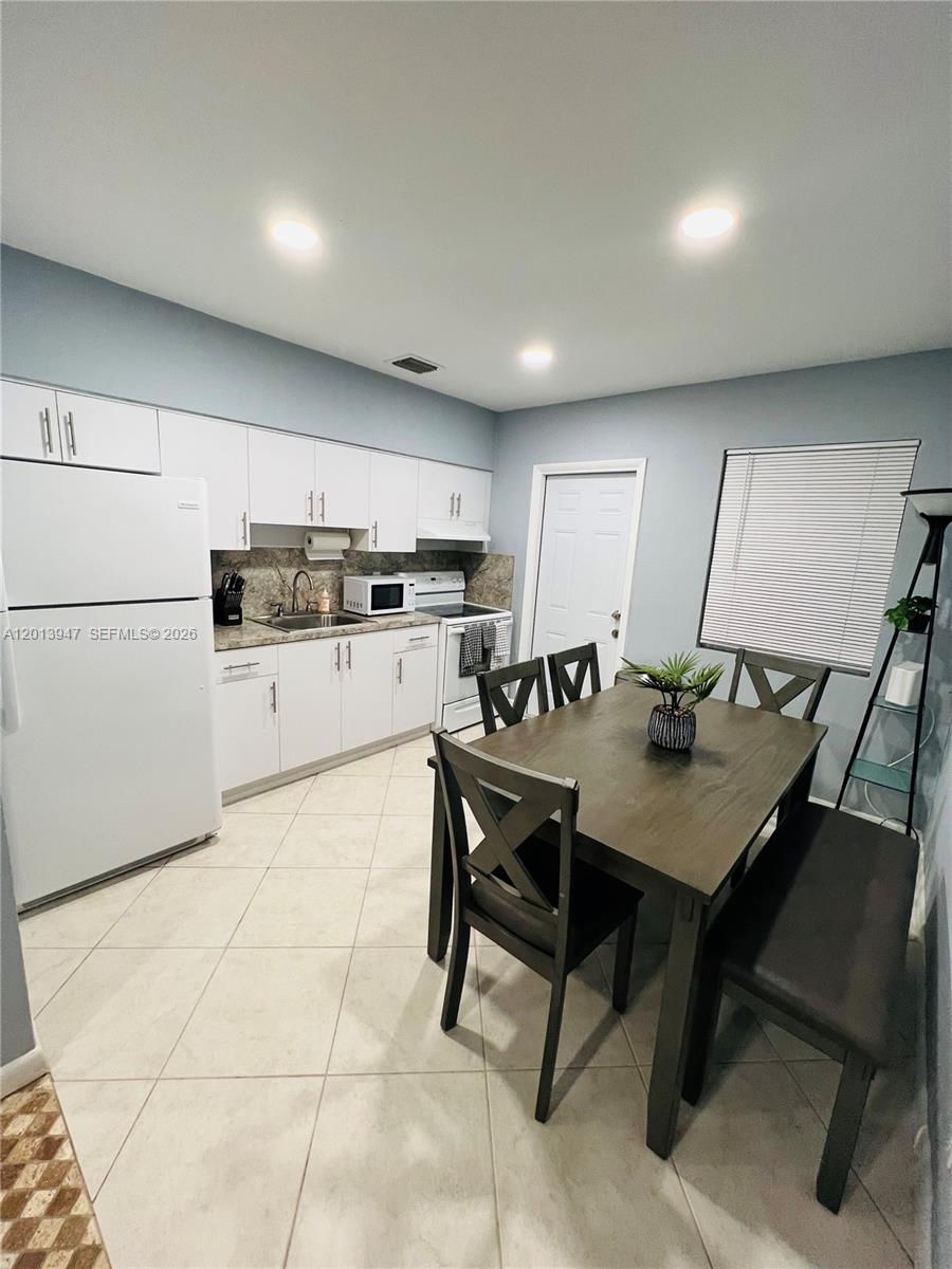 280 Northwest 55th Street, Unit 282 Miami, FL 33127 - Photo 15 of 19 a kitchen with stainless steel appliances kitchen island granite countertop a table chairs and a refrigerator
