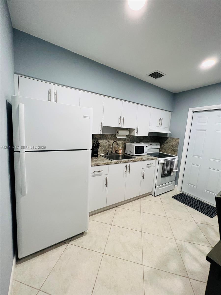 280 Northwest 55th Street, Unit 282 Miami, FL 33127 - Photo 16 of 19 a kitchen with a refrigerator a stove top oven and cabinets