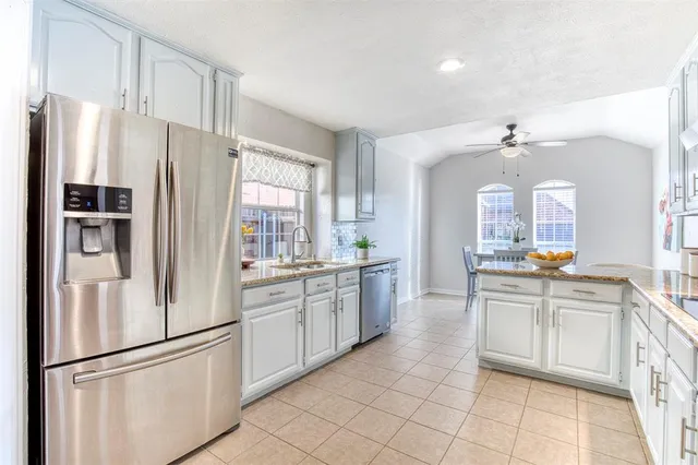 a large kitchen with white cabinets and stainless steel appliances