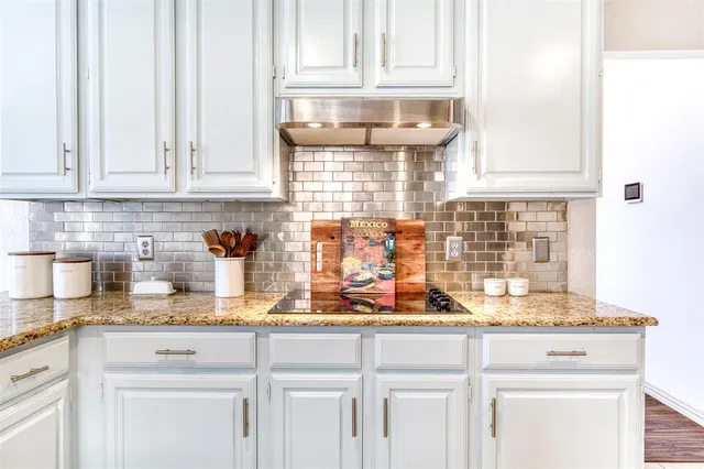 a kitchen with stainless steel appliances granite countertop white cabinets and a counter top space