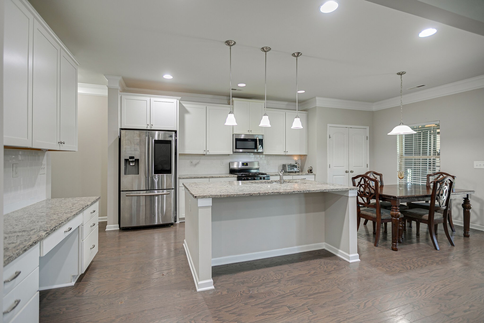 966 Carnation Drive Spring Hill, TN 37174 - Photo 15 of 31 a large white kitchen with lots of counter space dining table and stainless steel appliances