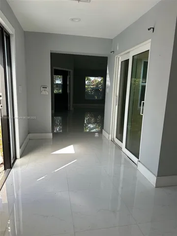 a view of a hallway with wooden floor and a living room