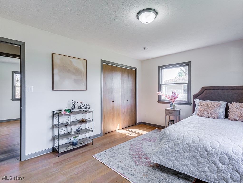 3995 Cottage Grove Road Uniontown, OH 44685 - Photo 18 of 29 Bedroom with baseboards, a textured ceiling, wood finished floors, and multiple windows